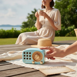 Hostecno retro vintage blue Bluetooth speaker with FM radio and TF card support, placed on a beach with a couple in the background.