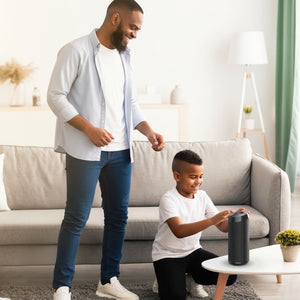 Hostecno Aquaboost 5W Boom Box portable Bluetooth speaker in black, with a father and son dancing in the living room.